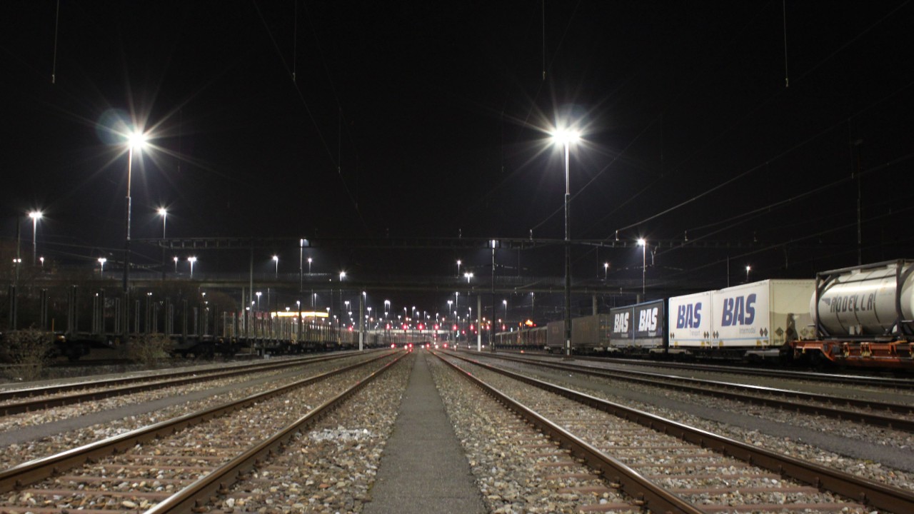 L’image montre un faisceau de voies de nuit, avec plusieurs files de rails éclairées.