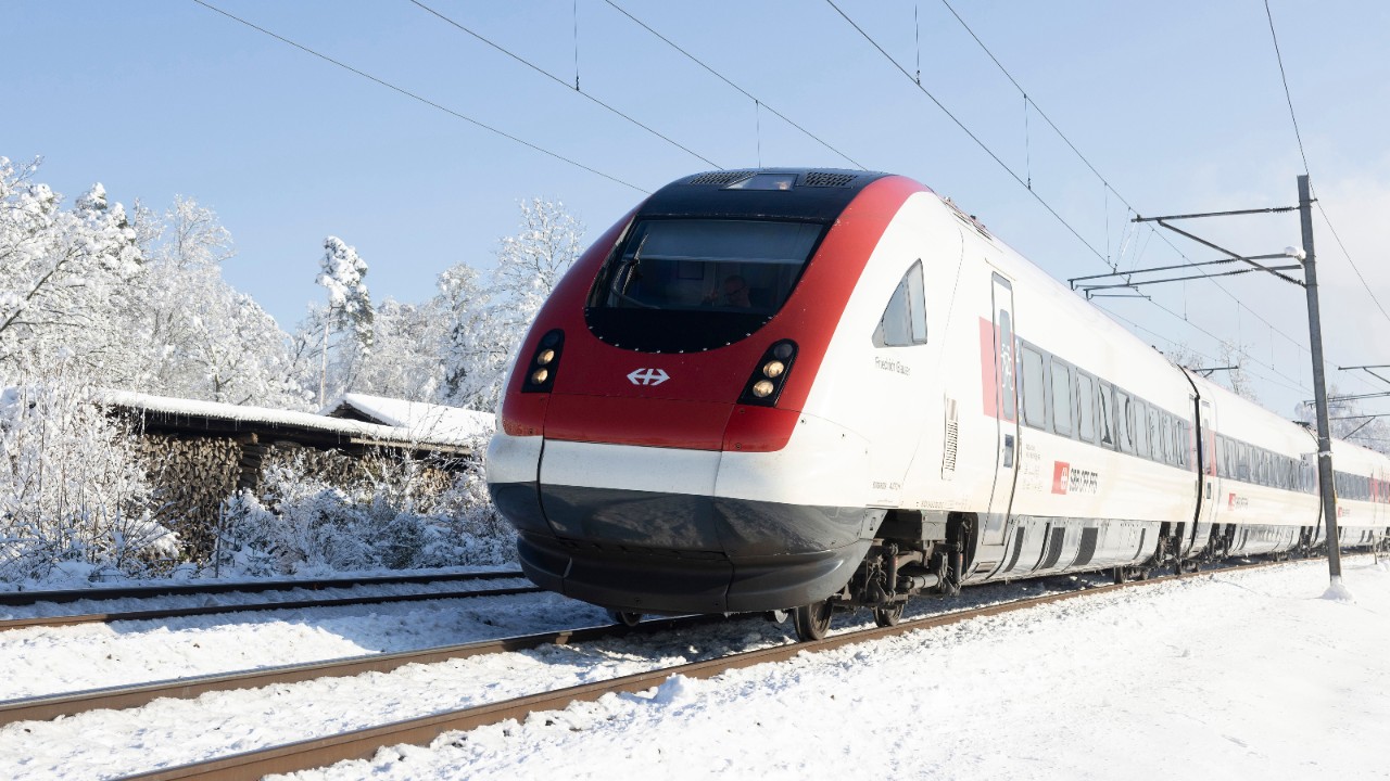 Un train InterCity pendulaire circule dans un paysage hivernal enneigé.