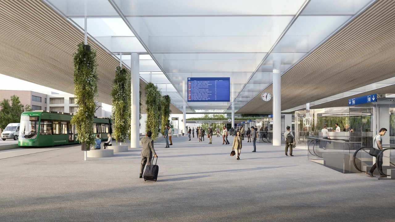 Visualisierung eines neuen Bahnhofboulevards mit breitem, überdachtem Weg zwischen Perrons und Stadt. Unter der lichtdurchlässigen Dachkonstruktion bewegen sich Reisende, Informationsanzeigen, Sitzgelegenheiten und begrünte Stützen strukturieren den offenen Raum. Auf der linken Seite hält ein Tram, rechts sind Zugänge zu weiteren Verkehrsmitteln und Anlagen sichtbar.