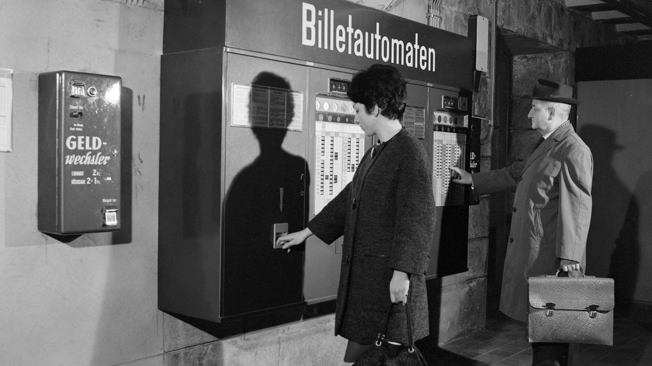 A man and a woman using a ticket machine, 1962.