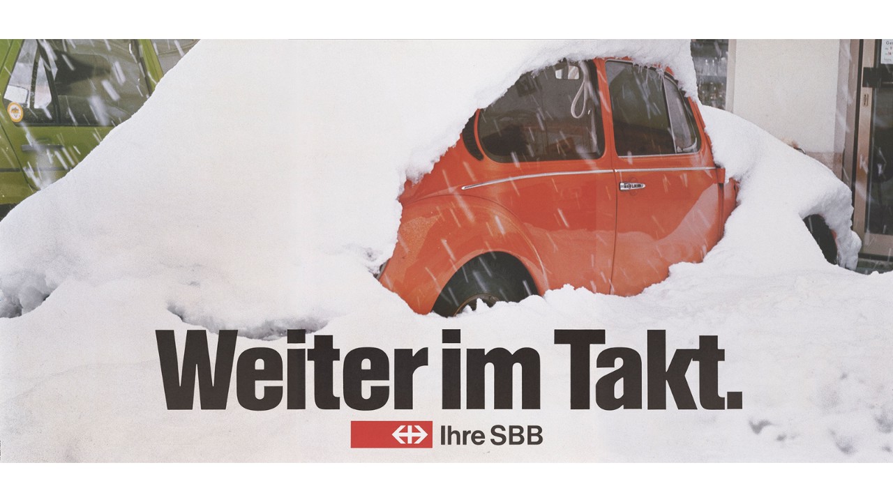 SBB poster advertising the introduction of the clock-face schedule with a snowbound red car. The slogan on the poster, “Weiter im Takt”, means “Right on schedule”.