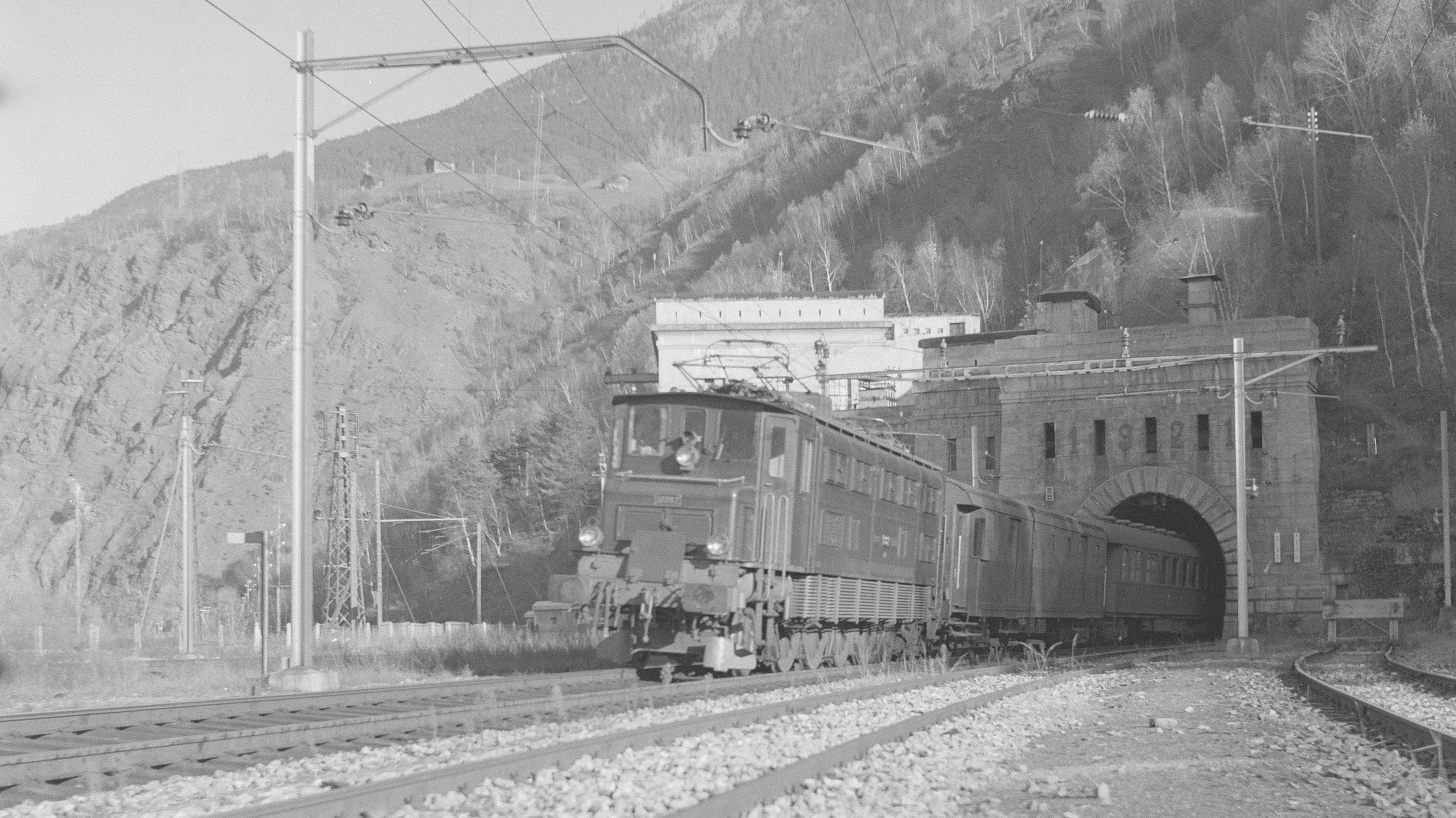 Black and white photograph of a train exiting the Simplon tunnel north portal, 1954.