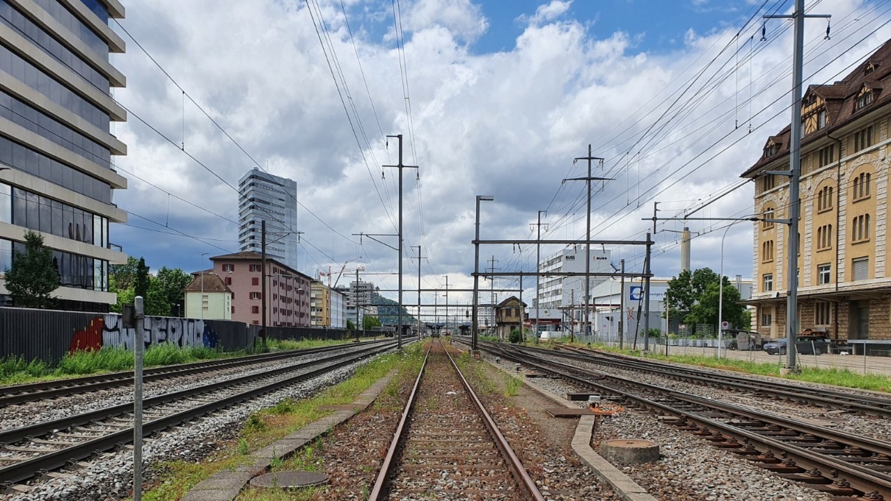 Das Foto vom Juni 2021 zeigt die östliche Einfahrt zum Bahnhof Pratteln von Osten in Richtung Basel, beziehungsweise Westen gesehen. Hinten im Bild sind die östlichen Enden der drei Perrons zu sehen.