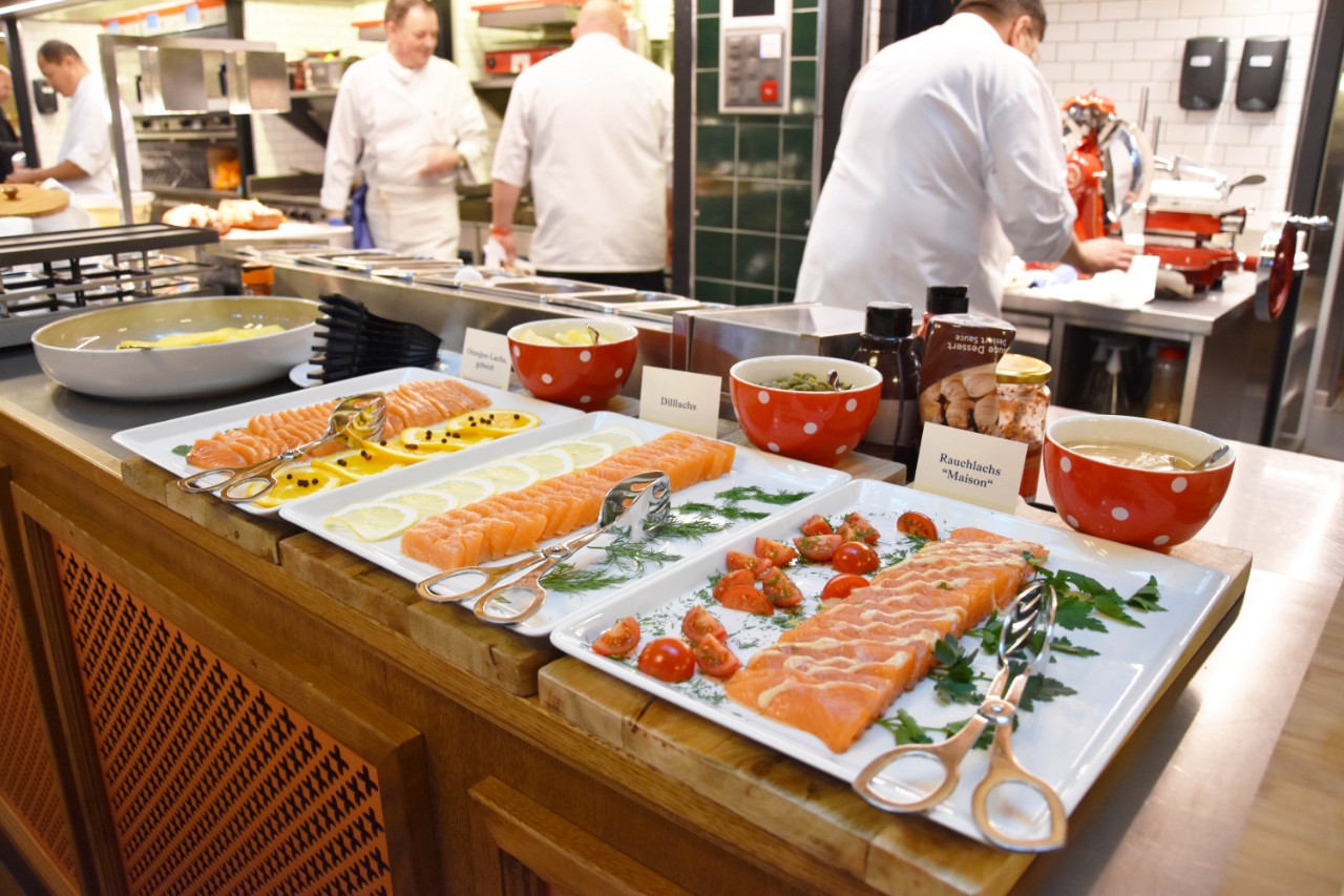 Drei Sorten hausgebeizter Lachs auf dem Buffet der Brasserie Federal, dahinter werkelt emsiges Küchenpersonal in weissen Kitteln.
